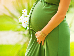 Featured Image for pregnant belly green dress and daisies