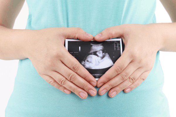 heart hands over belly with sonogram