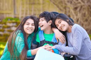 Featured Image for sisters hugging disabled brother in wheelchair