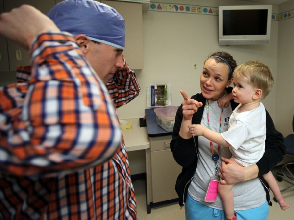 Child life specialist Megan Flaker holds Jordan while Randy ties on an OR hat