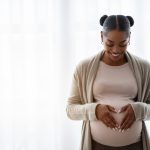 Is marijuana safe to use during pregnancy? What parents should know Smiling young black pregnant woman holding hands on big belly